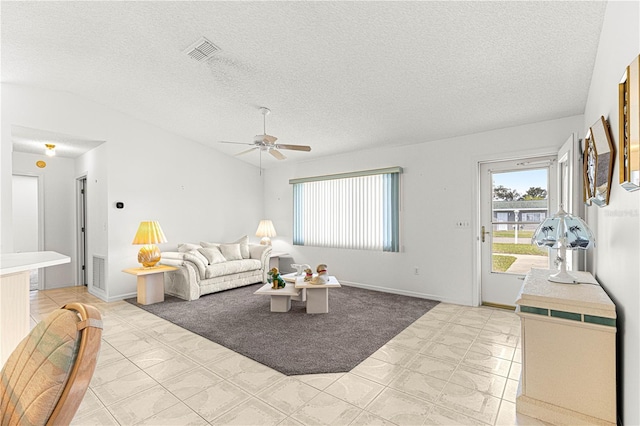 living room featuring a ceiling fan, lofted ceiling, visible vents, and a textured ceiling