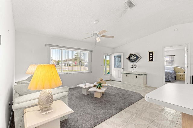 living room featuring a textured ceiling, visible vents, vaulted ceiling, and a ceiling fan