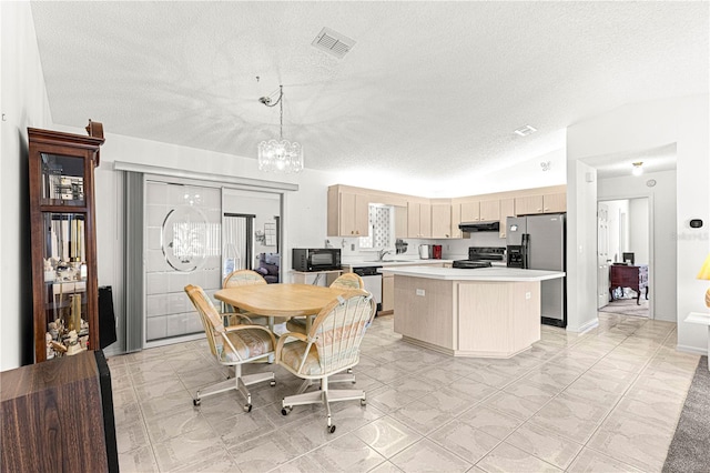 kitchen featuring under cabinet range hood, a kitchen island, visible vents, light countertops, and black appliances