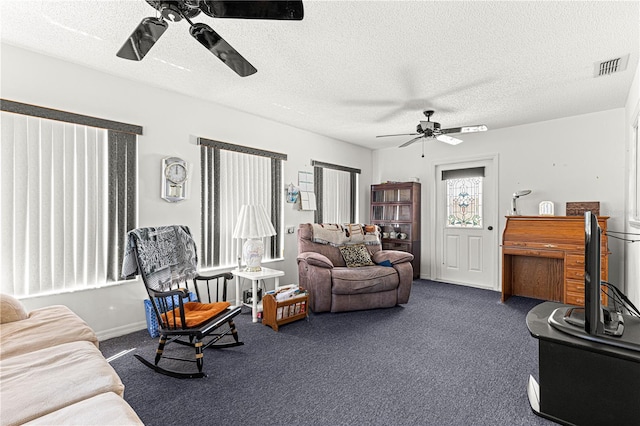 carpeted living area featuring baseboards, ceiling fan, visible vents, and a textured ceiling