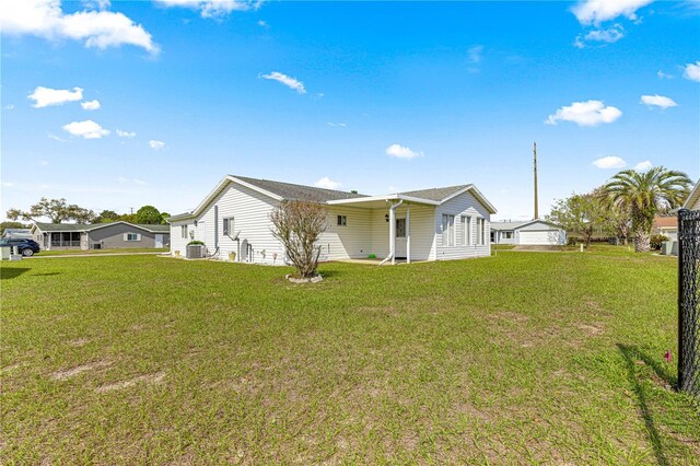 rear view of house featuring a lawn and central AC unit