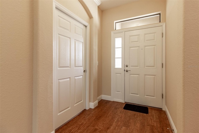 foyer with a textured wall, wood finished floors, and baseboards