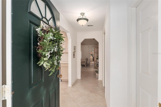 entrance foyer with light tile patterned floors, visible vents, and arched walkways