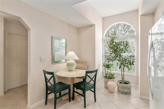 dining area with light tile patterned floors, baseboards, and arched walkways