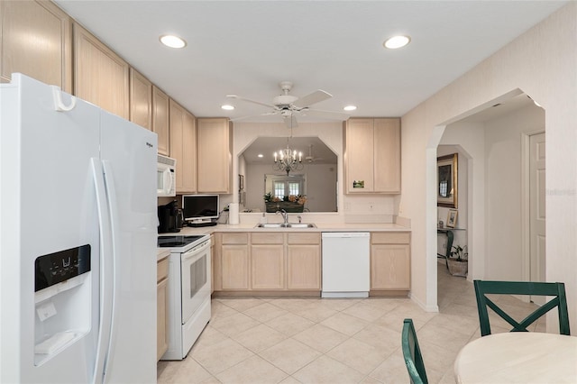 kitchen featuring white appliances, arched walkways, light countertops, light brown cabinets, and a sink