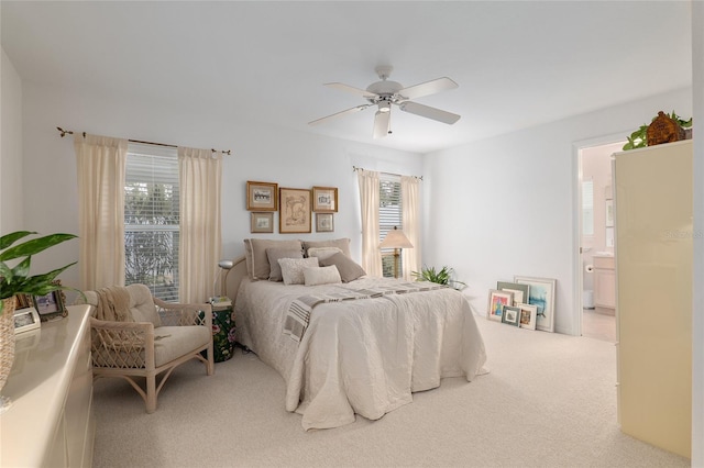 carpeted bedroom featuring multiple windows, ceiling fan, and ensuite bath