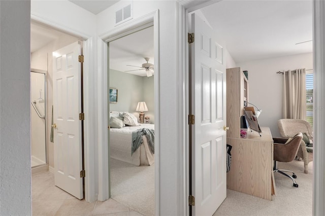 hallway featuring light tile patterned flooring, visible vents, and light colored carpet