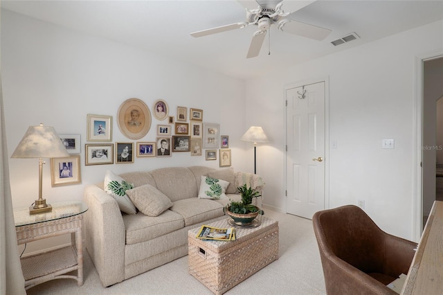 living room featuring ceiling fan, visible vents, and light colored carpet