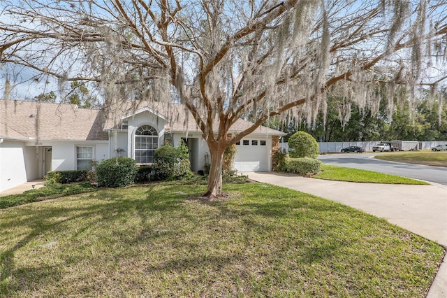 view of front of house with driveway, an attached garage, fence, a front yard, and stucco siding