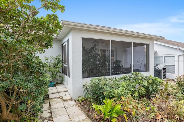 view of property exterior featuring a sunroom and stucco siding