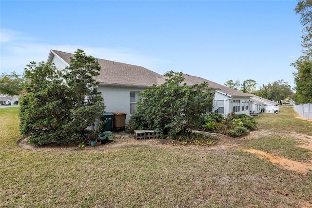 back of property with a lawn and stucco siding