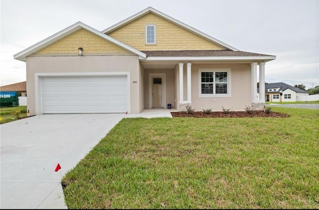 view of front of property featuring an attached garage, driveway, a front lawn, and stucco siding