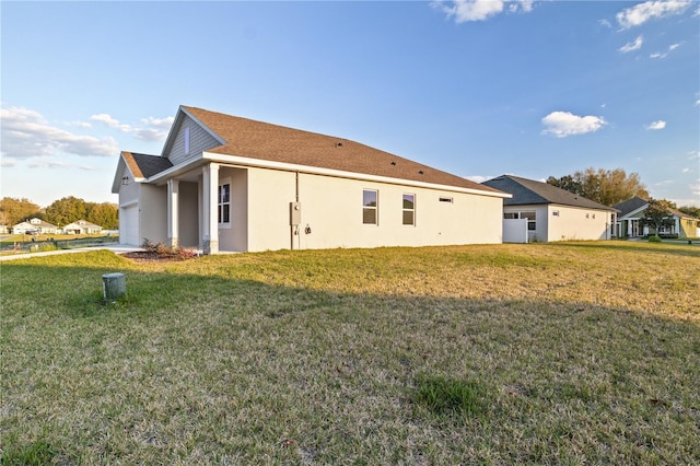 view of side of property with a garage, stucco siding, and a lawn