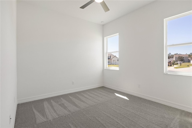 carpeted empty room with ceiling fan and baseboards