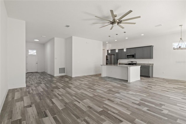 kitchen featuring light wood-style floors, ceiling fan with notable chandelier, visible vents, appliances with stainless steel finishes, and open floor plan