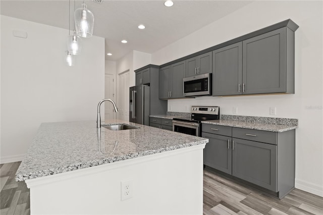 kitchen with light stone countertops, light wood-style flooring, recessed lighting, a sink, and stainless steel appliances