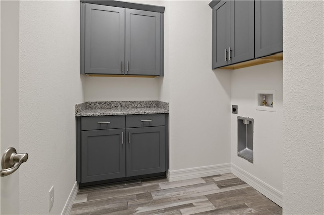 washroom featuring baseboards, light wood-type flooring, cabinet space, electric dryer hookup, and hookup for a washing machine