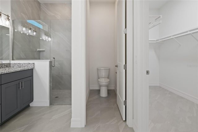 bathroom featuring a shower stall, a walk in closet, vanity, and toilet