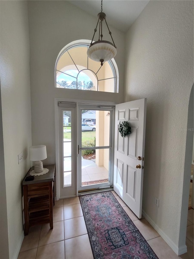 entrance foyer with light tile patterned floors, a high ceiling, and baseboards