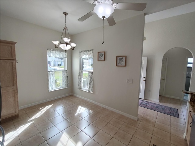 empty room with light tile patterned floors, baseboards, and arched walkways