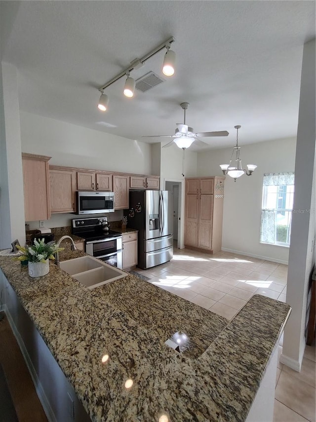 kitchen featuring a peninsula, appliances with stainless steel finishes, a sink, and visible vents