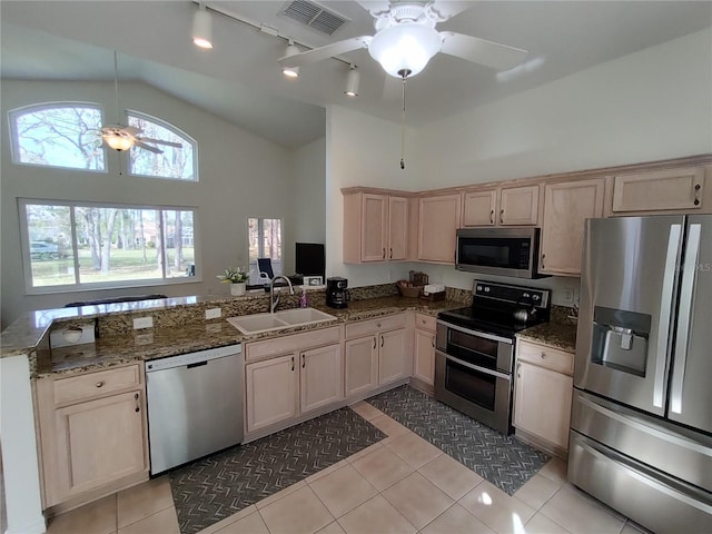 kitchen featuring stainless steel appliances, a peninsula, a sink, visible vents, and light stone countertops