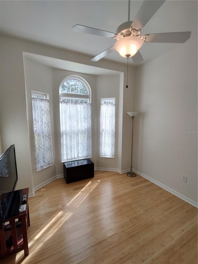 interior space featuring ceiling fan, light wood-style flooring, and baseboards