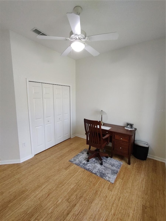 office with light wood-style flooring, visible vents, ceiling fan, and baseboards