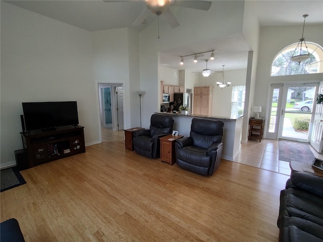 living room with a high ceiling, light wood-type flooring, and a ceiling fan