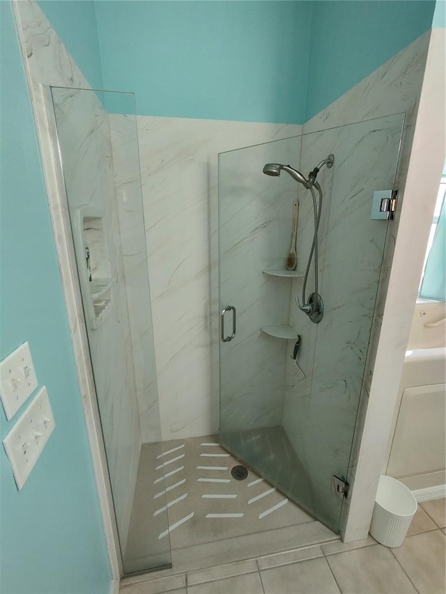 bathroom featuring tile patterned flooring and a marble finish shower