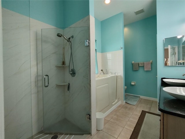 bathroom with double vanity, visible vents, a sink, a shower stall, and tile patterned floors