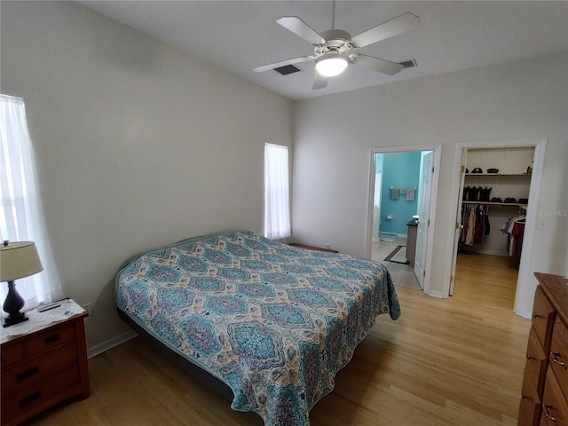 bedroom with baseboards, ensuite bath, a spacious closet, light wood-type flooring, and a closet