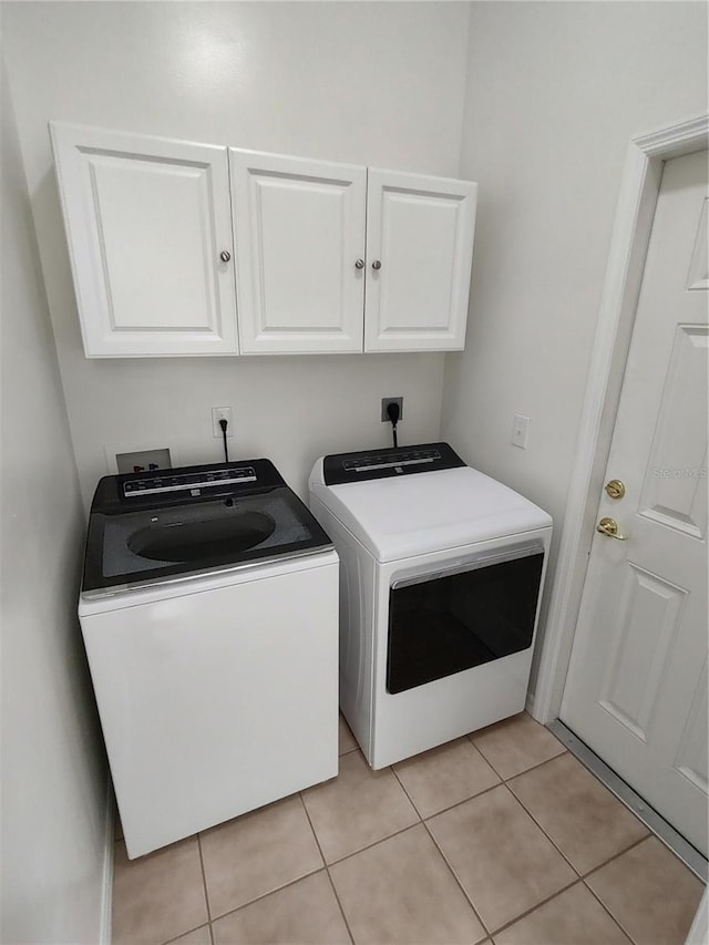 washroom with light tile patterned floors, independent washer and dryer, and cabinet space