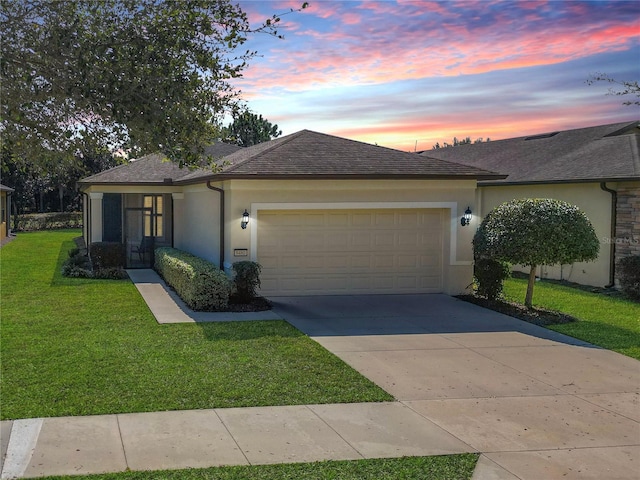 view of front of property with driveway, a garage, a shingled roof, a front lawn, and stucco siding