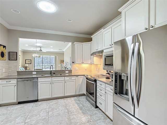 kitchen with tasteful backsplash, white cabinets, appliances with stainless steel finishes, crown molding, and a sink