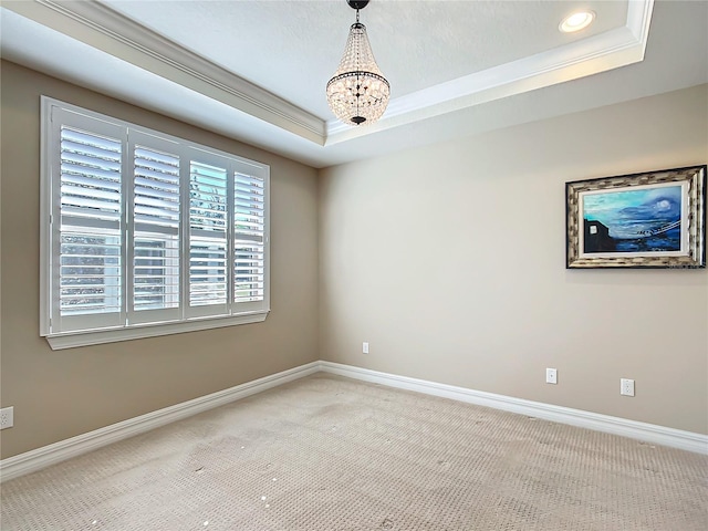 empty room featuring baseboards, ornamental molding, a tray ceiling, carpet flooring, and a notable chandelier