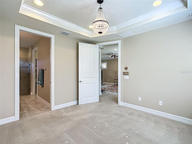 unfurnished bedroom featuring a tray ceiling, light colored carpet, visible vents, and baseboards