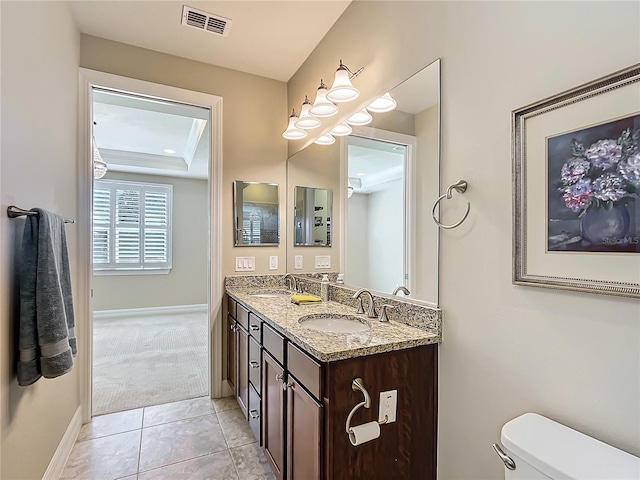 bathroom featuring double vanity, a tray ceiling, a sink, and visible vents