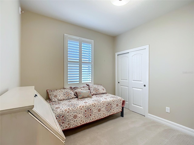 bedroom featuring baseboards, a closet, and light colored carpet