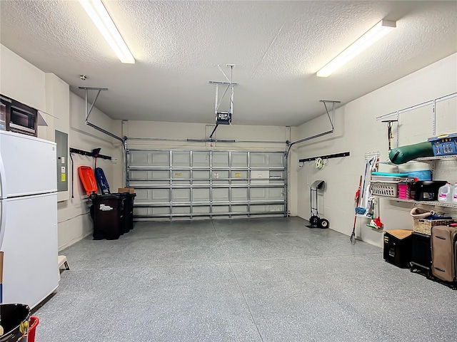 garage with a garage door opener, freestanding refrigerator, and electric panel