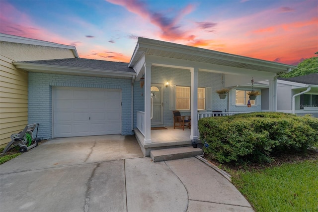 view of front of home featuring driveway, an attached garage, a porch, and brick siding