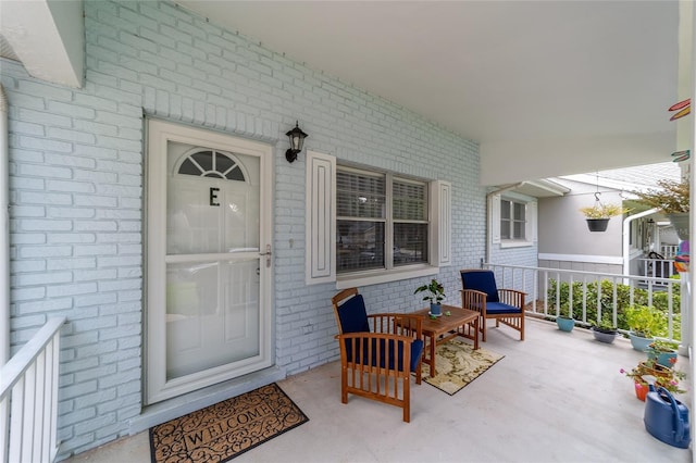 doorway to property featuring a porch and brick siding