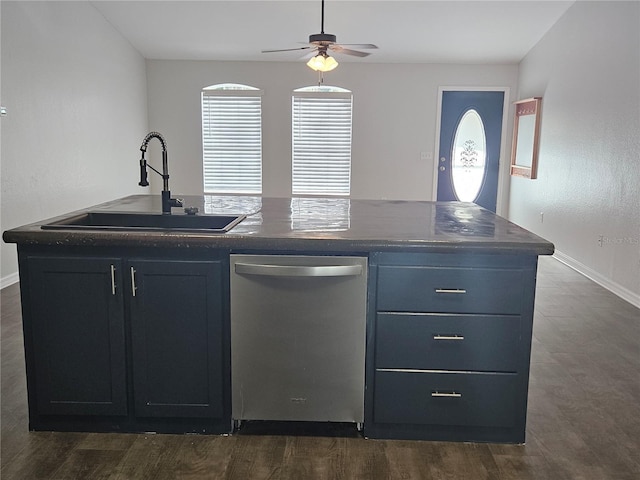 kitchen with a sink, a ceiling fan, stainless steel dishwasher, dark countertops, and a center island with sink