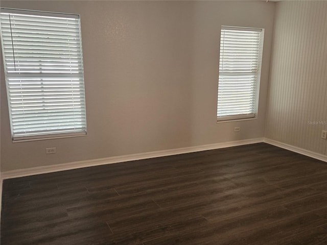 spare room featuring dark wood finished floors and baseboards