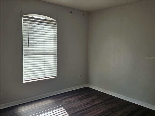 empty room featuring dark wood-style floors and baseboards