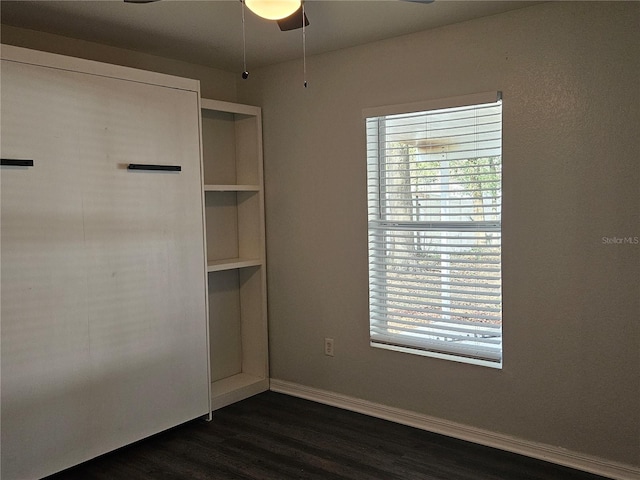 interior space featuring a ceiling fan, baseboards, and dark wood-style flooring