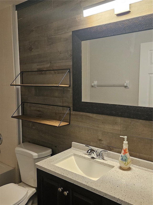 bathroom featuring toilet, decorative backsplash, a bath, and vanity