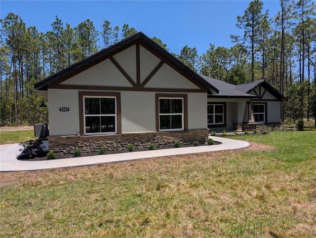 view of front facade with stucco siding, a front yard, and stone siding