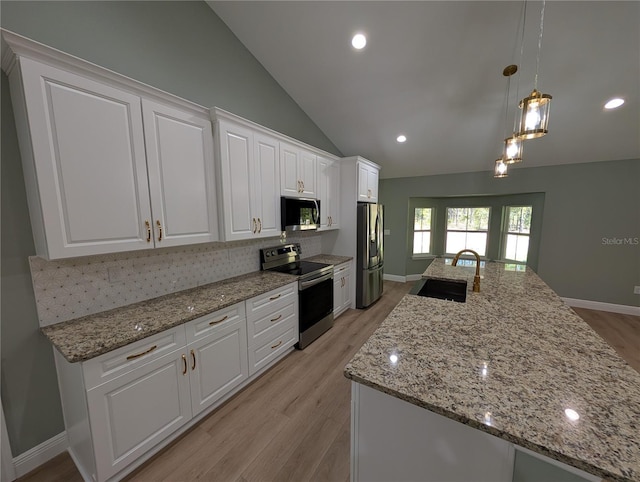 kitchen featuring white cabinets, a sink, stainless steel appliances, decorative backsplash, and light wood-type flooring