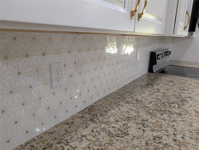 room details featuring light stone counters, decorative backsplash, white cabinetry, and electric stove